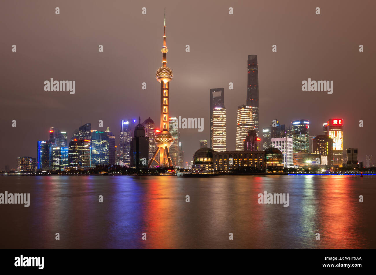 Skyline der Stadt Shanghai Pudong bei Nacht mit dem Oriental Pearl TV Tower und Lichtreflexionen des Huangpu Flusses, Shanghai, China Stockfoto