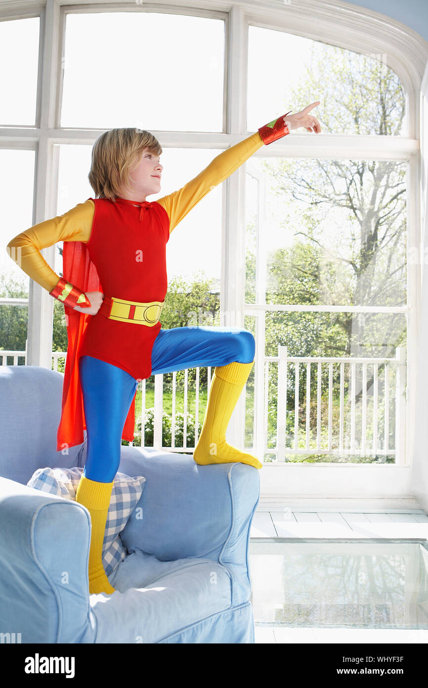 Die volle Länge eines Jungen in superman Kostüm stehen auf Sessel und nach  oben Stockfotografie - Alamy