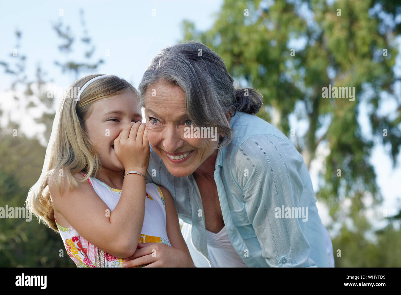 Nahaufnahme eines jungen Mädchens flüstern in der Großmutter Ohr im Freien Stockfoto