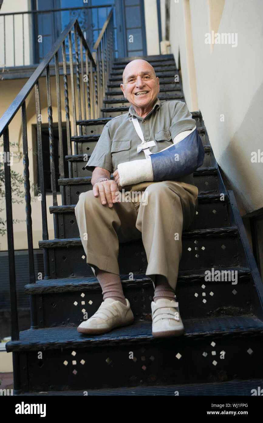 Mann mit gebrochenen Arm sitzen auf Treppen Stockfoto