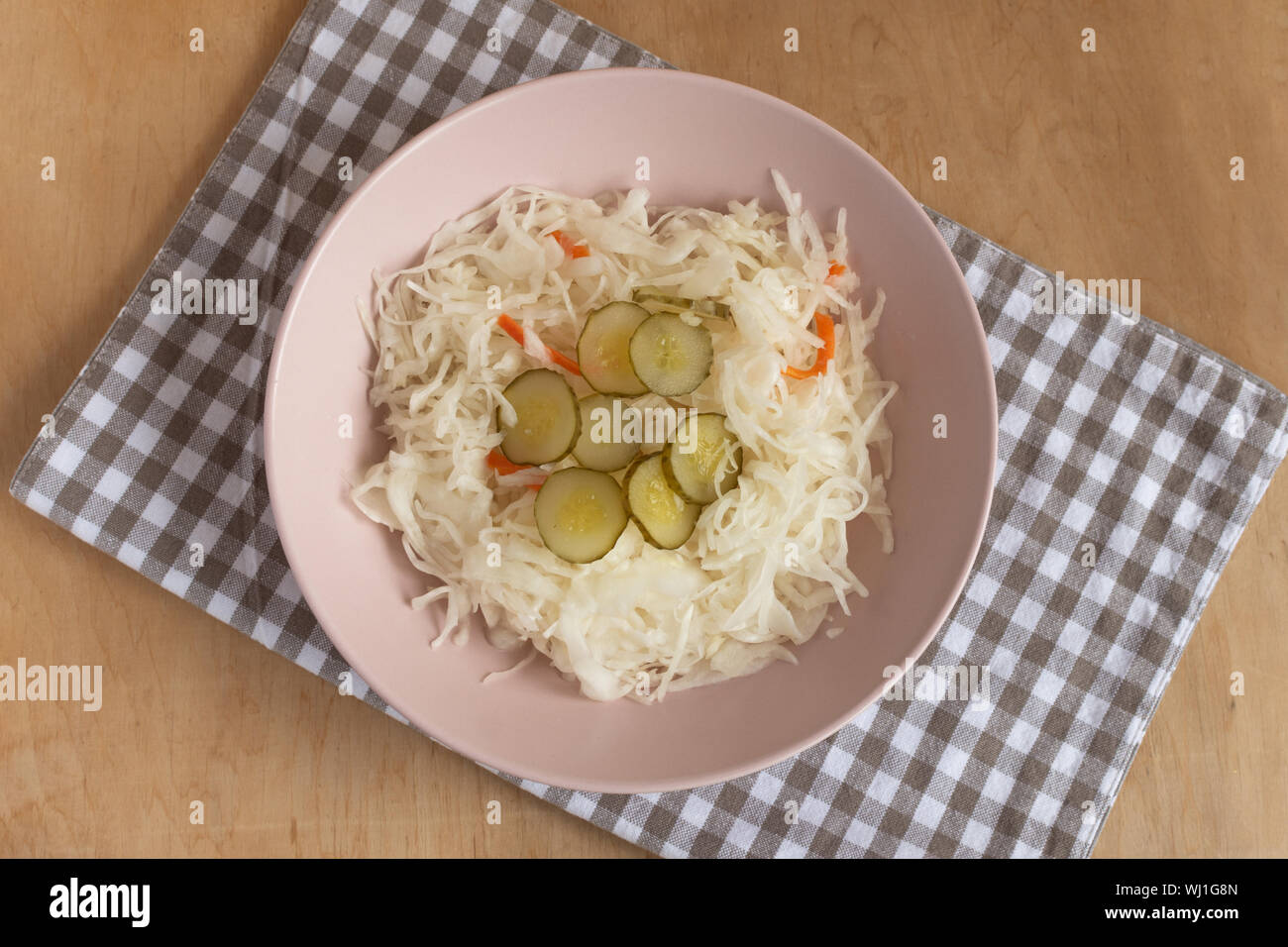 Sauerkraut mit picle Gurken in eine Schüssel auf Pastell rosa farbigen Hintergrund der Ansicht von oben. Fermentiertes Gemüse. Stockfoto