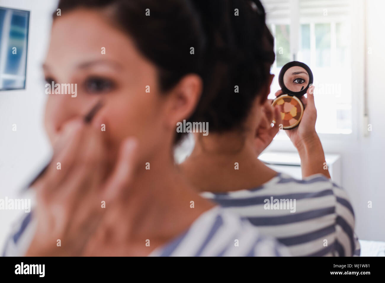 Junge Latina setzen auf Make-up vor dem Spiegel Malerei ihr Auge Linie Stockfoto