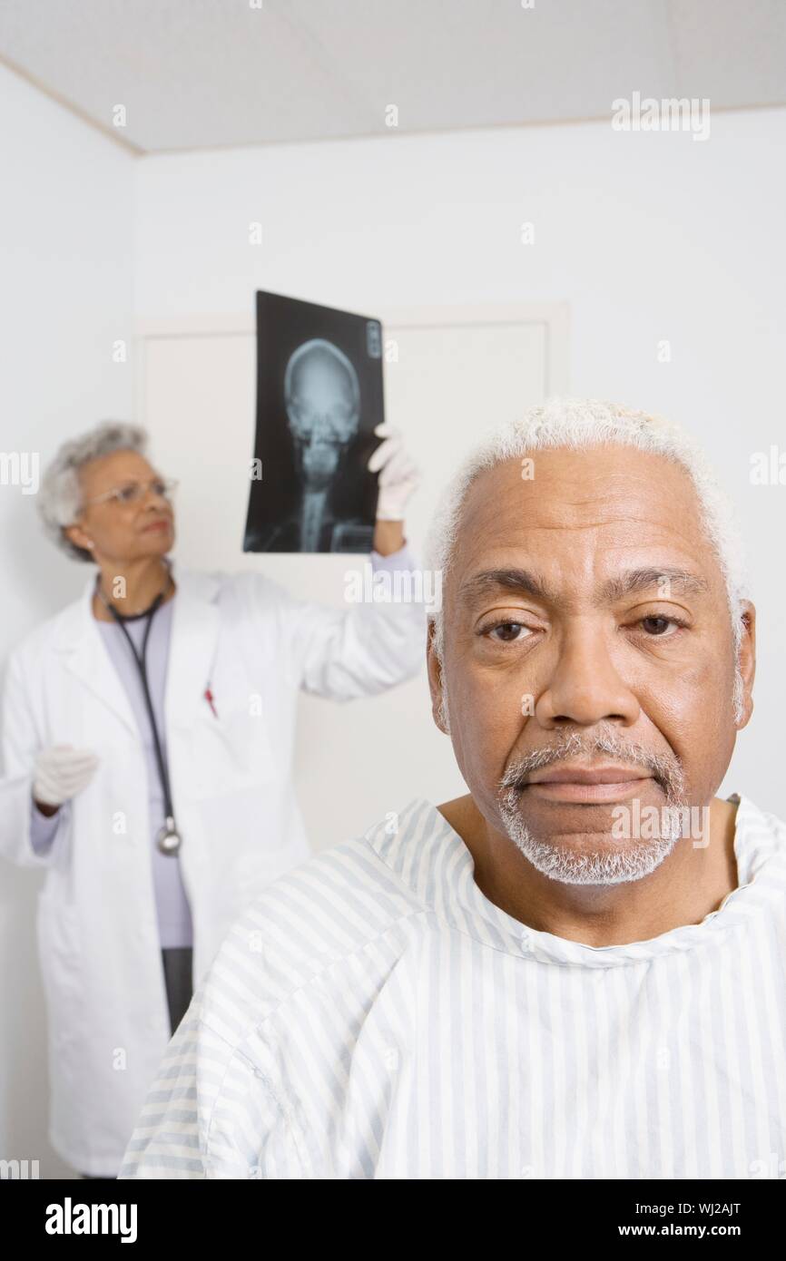 Portrait von älteren männlichen Patienten mit Arzt Prüfung x-ray Bericht im Hintergrund Stockfoto