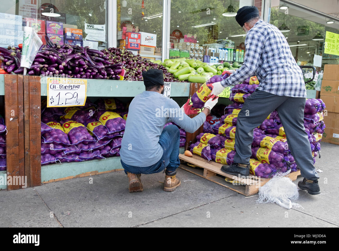 2 Sikh Männer einen Versand der große Taschen der Zwiebeln entladen. Am Apna Basar auf der 37th Avenue in Jackson Heights, Queens, New York City Stockfoto