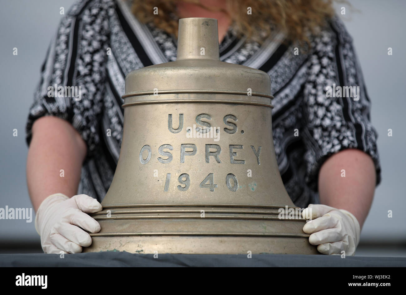 Heloise Warner, die Handelnden Empfänger des Wracks an die Maritime and Coastguard Agency in Southampton, mit der Glocke von der USS Osprey, die an die amerikanischen Behörden zurückgegeben werden. Das Schiff sank am 5. Juni 1944, die Nacht vor der Operation Overlord begann, als sie schlug eine Mine und sank um 5:00 Uhr mit dem Verlust von sechs Männern, südlich der Isle of Wight. Stockfoto