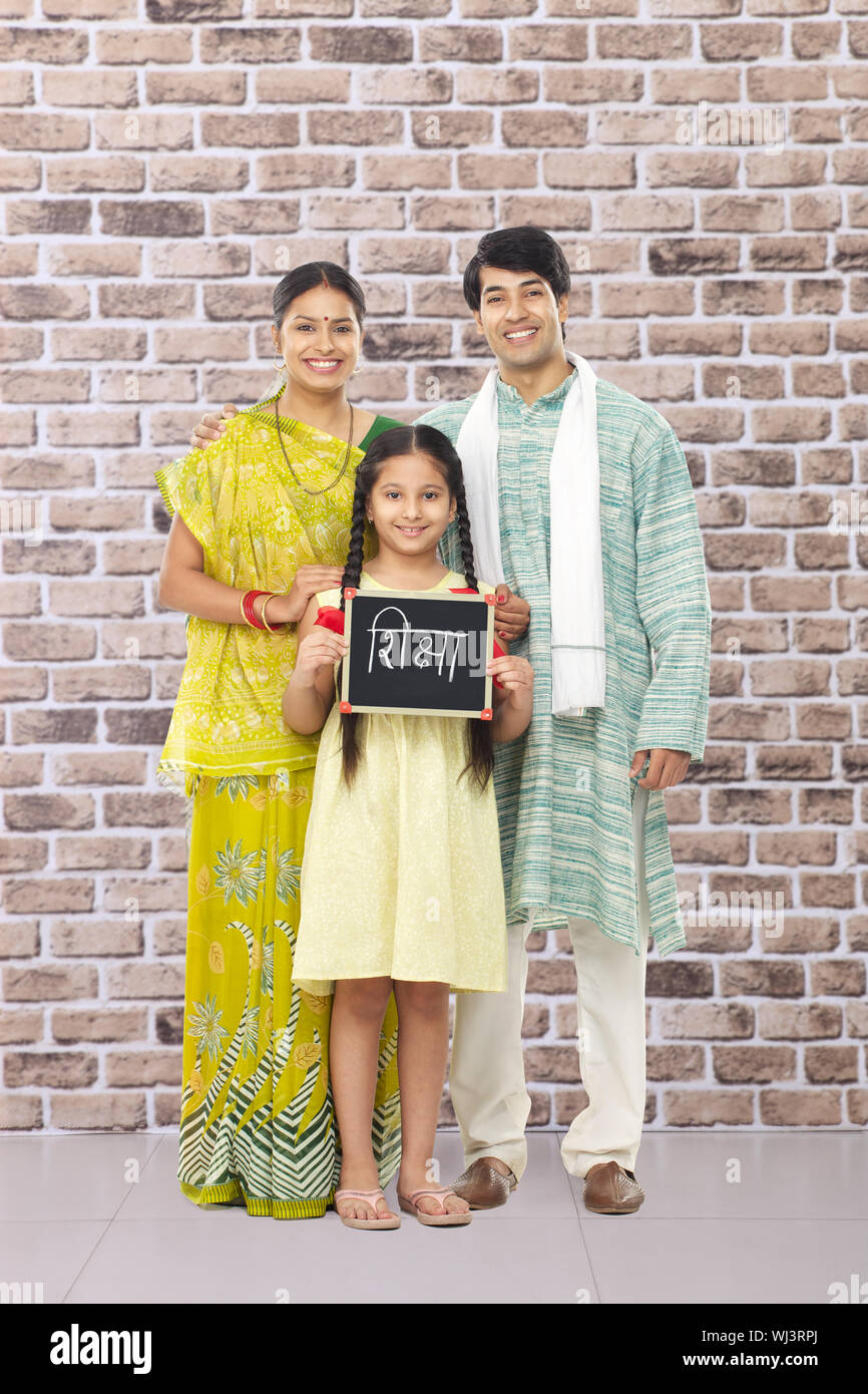 Mädchen hält einen Schiefer 'Shiksha' geschrieben auf sie stehen mit Ihre Eltern Stockfoto