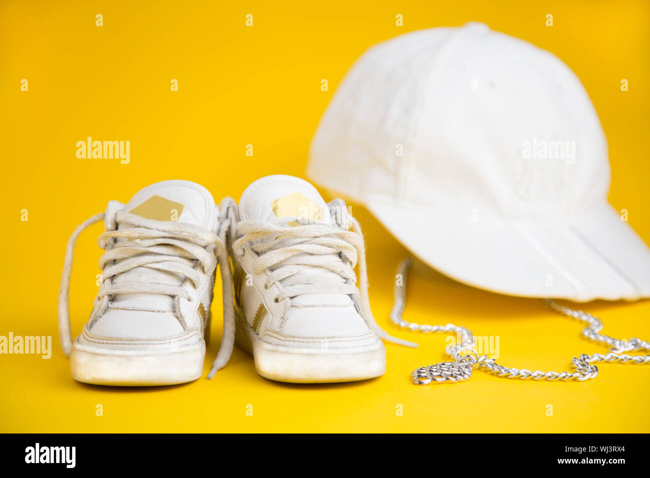 In der Nähe von Weißen Sneaker Schuhe mit Kappe und Kette auf gelbem  Hintergrund Stockfotografie - Alamy