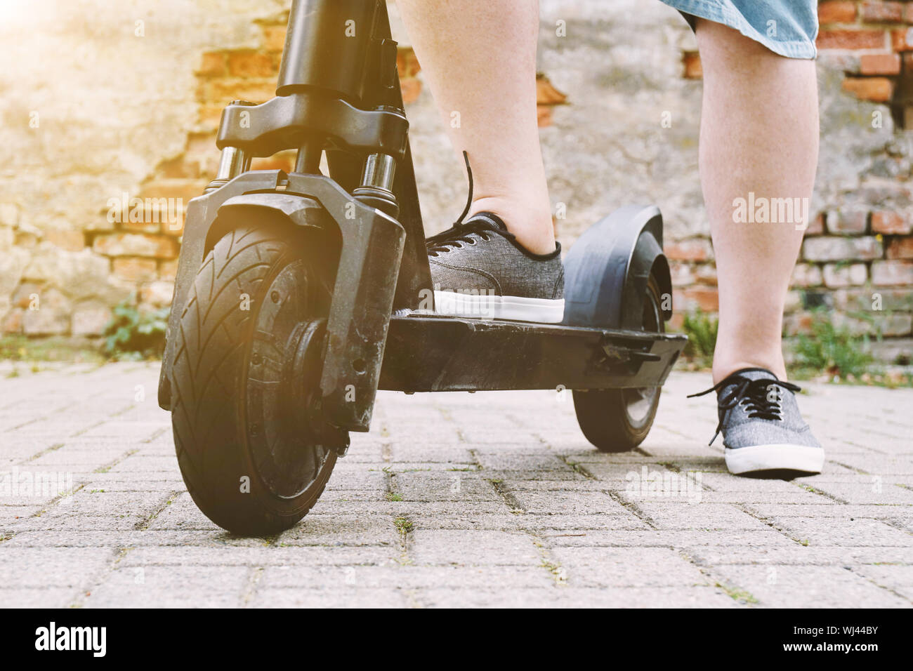 Beine der unkenntlich Person mit elektrischen kick Scooter oder E-Roller - e-mobility oder Micro-Mobilität hipster Lifestyle trend Konzept mit Sun flare Filter Stockfoto
