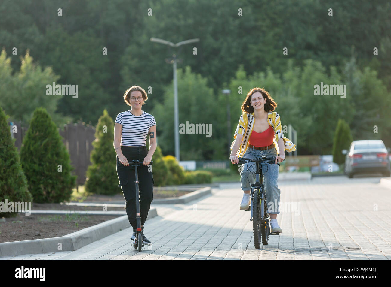 Frauen Freunde Reiten Fahrrad und Roller auf der Straße Stockfoto