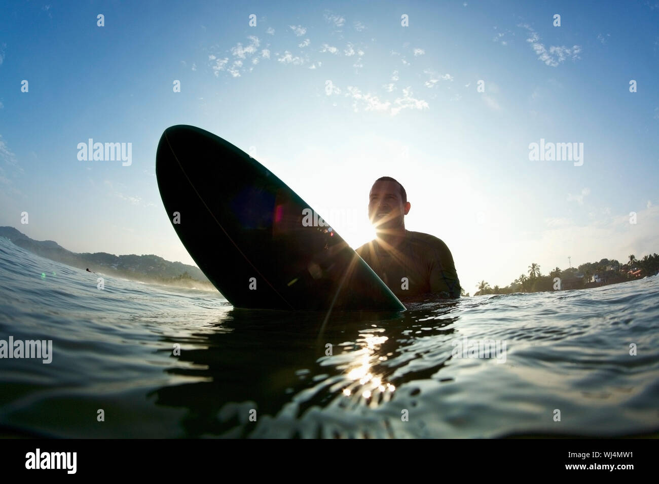 Silhouette männliche Surfer gebietsübergreifende Surfboard im sonnigen Ozean Stockfoto