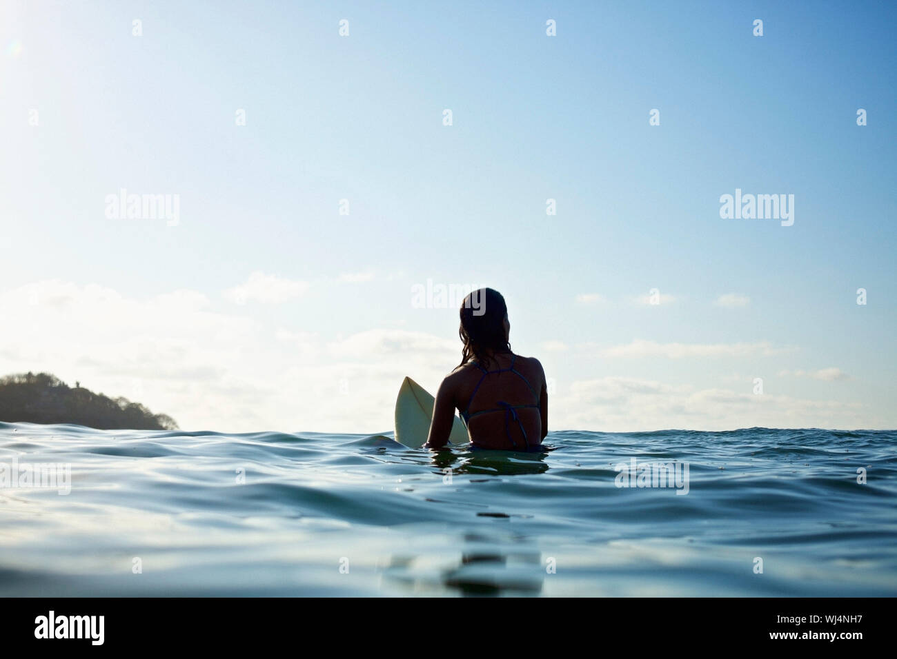 Silhouette weibliche surfer Surfbrett gebietsübergreifenden, warten im sonnigen blauen Ozean Stockfoto