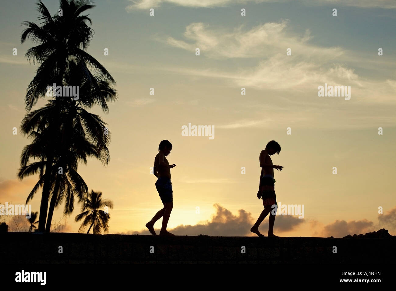 Silhouette Boys durch die Sims gegen ruhige Sonnenuntergang Himmel Stockfoto