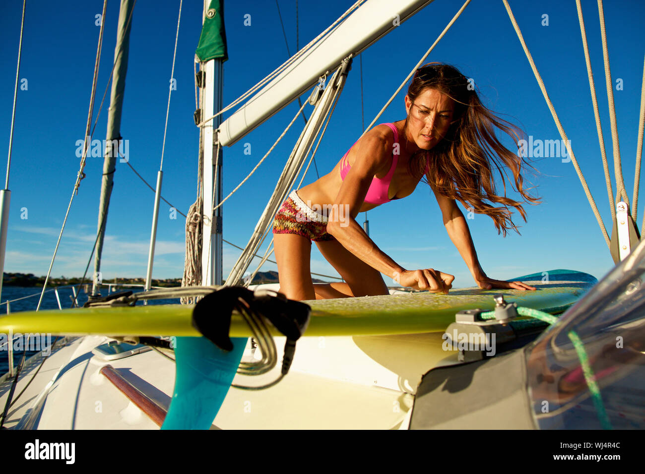Weibliche surfer waxing Surfboard an sonnigen Segelboot Stockfoto
