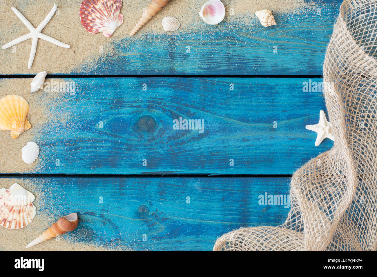 Urlaub Grenze mit Muscheln, Seesterne, Sand und Fischernetz auf Blau Holz- Hintergrund Stockfoto