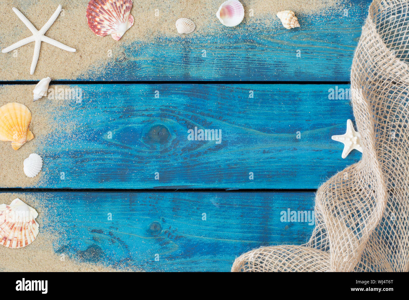 Ferienhäuser Grenze mit Muscheln, Seesterne, Sand und Fischernetz auf Blau Holz- Hintergrund Stockfoto