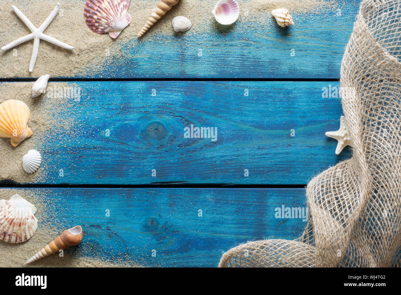 Urlaub Grenze mit Muscheln, Seesterne, Sand und Fischernetz auf Blau Holz- Hintergrund Stockfoto
