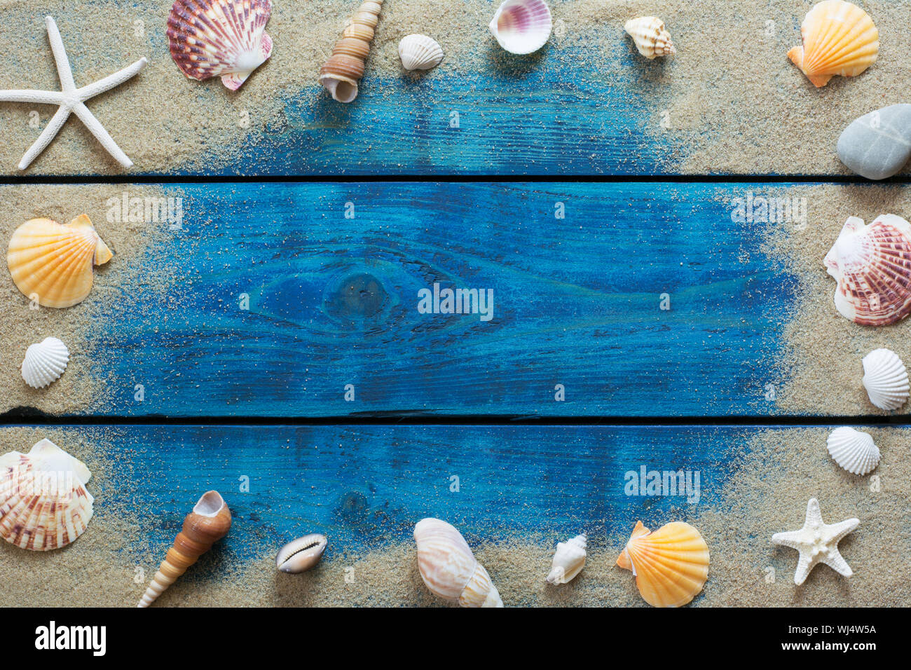 Sommer Grenze mit verschiedenen Muscheln, Seesterne und Sand auf Blau Holz- Hintergrund Stockfoto