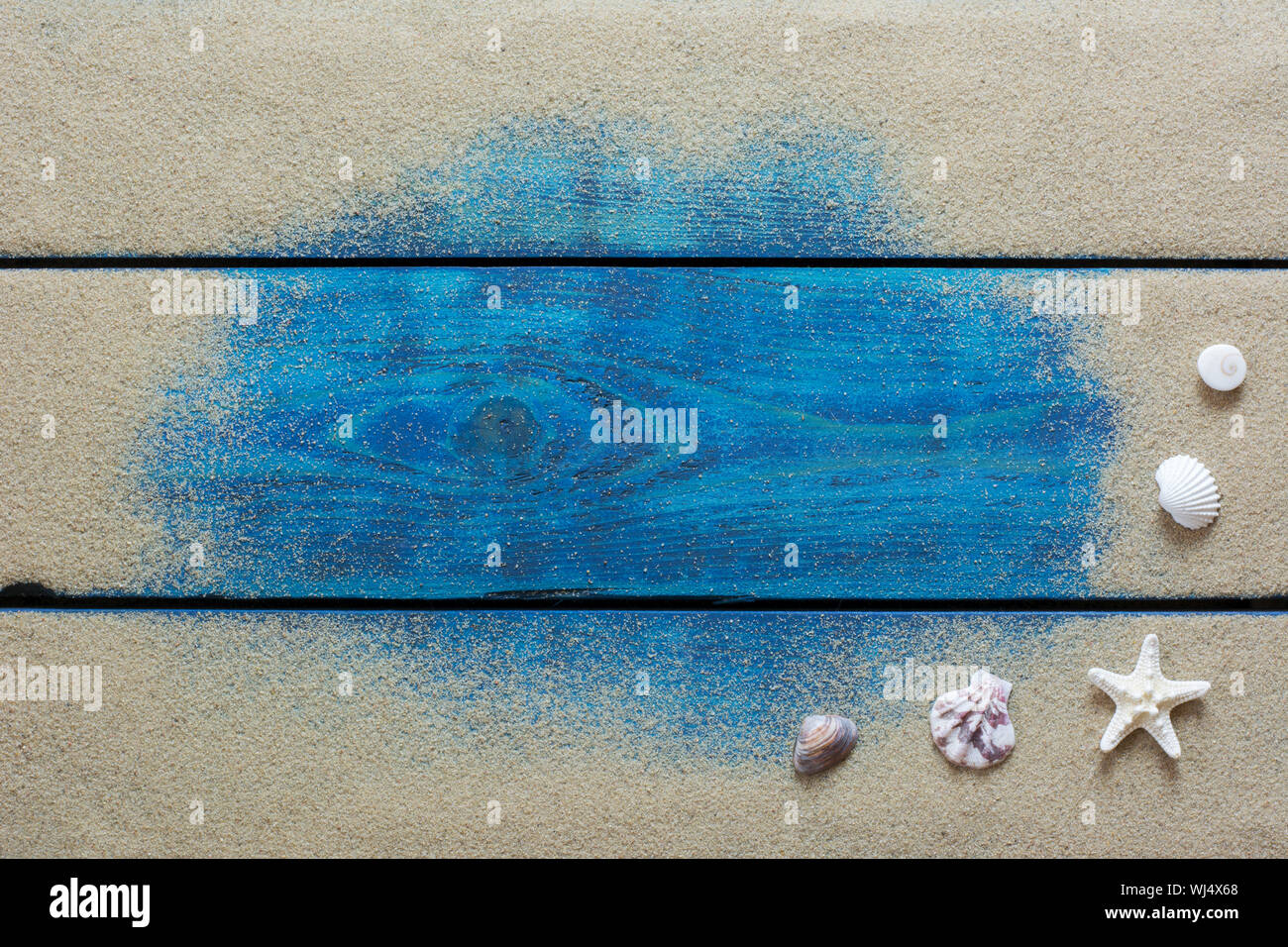 Sommer Hintergrund mit gelben Sand, Seesterne und Muscheln auf Blau Holz- Hintergrund Stockfoto