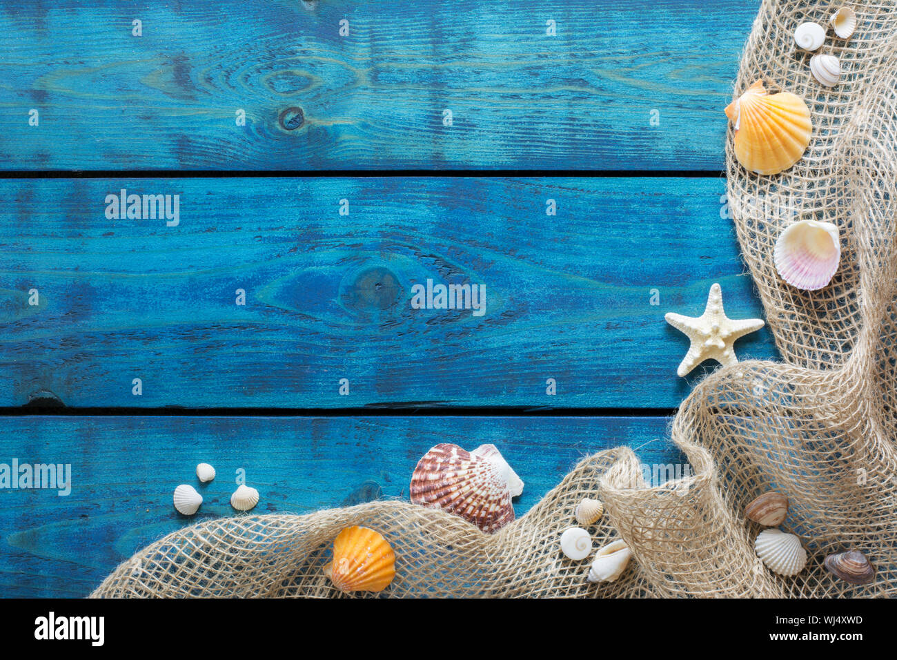 Ferienhäuser Grenze mit bunten Muscheln, Seesternen und Fischen net auf Blau Holz- Hintergrund Stockfoto