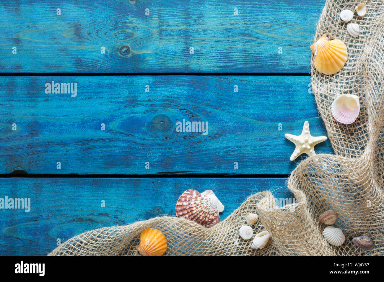 Ferienhäuser Grenze mit bunten Muscheln, Seesternen und Fischen net auf Blau Holz- Hintergrund Stockfoto