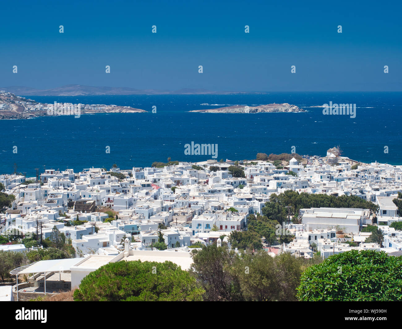 Viele weiße Häuser am Ufer des ruhigen, blauen Meer am wolkenlosen sonnigen Tag auf der Insel Mykonos in Griechenland Stockfoto