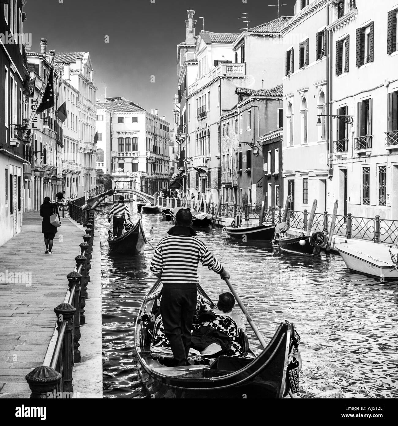 Gondeln vorbei an kleinen Kanal unter den alten historischen Häusern und Brücke in Venedig, Italien. Schwarz-weiß-Bild. Stockfoto