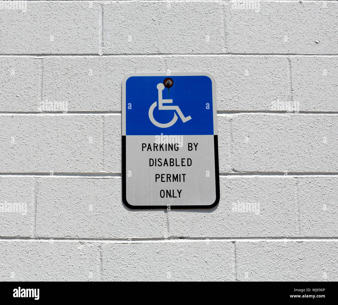 Blau und Weiß handicap Behinderte parken Schild zu einem gemalten konkrete Block Wand verschraubt. Stockfoto