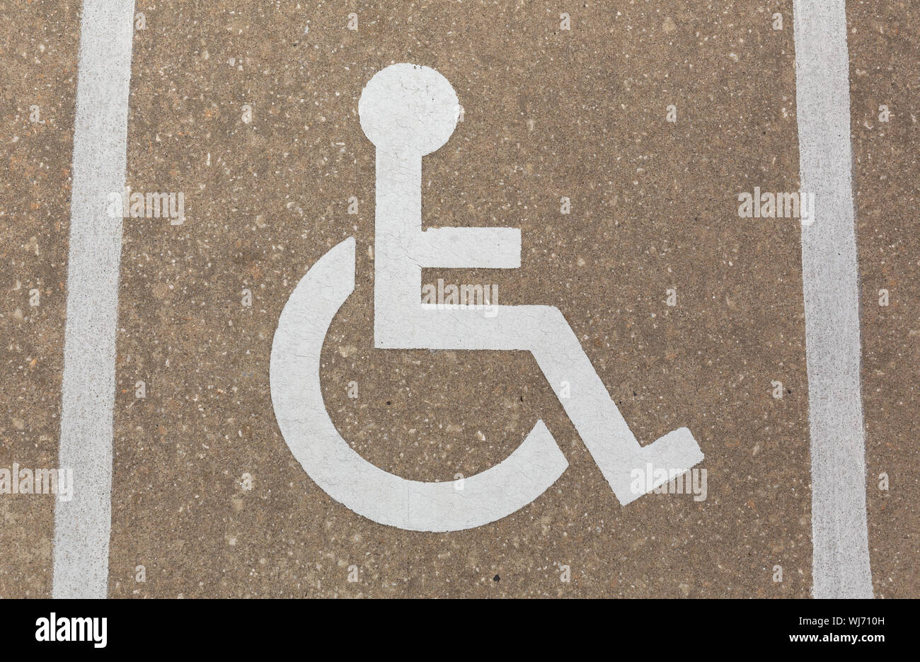Eine weiß lackierte handicap Zeichen auf Beton mit zwei weißen Streifen bemalt. Stockfoto
