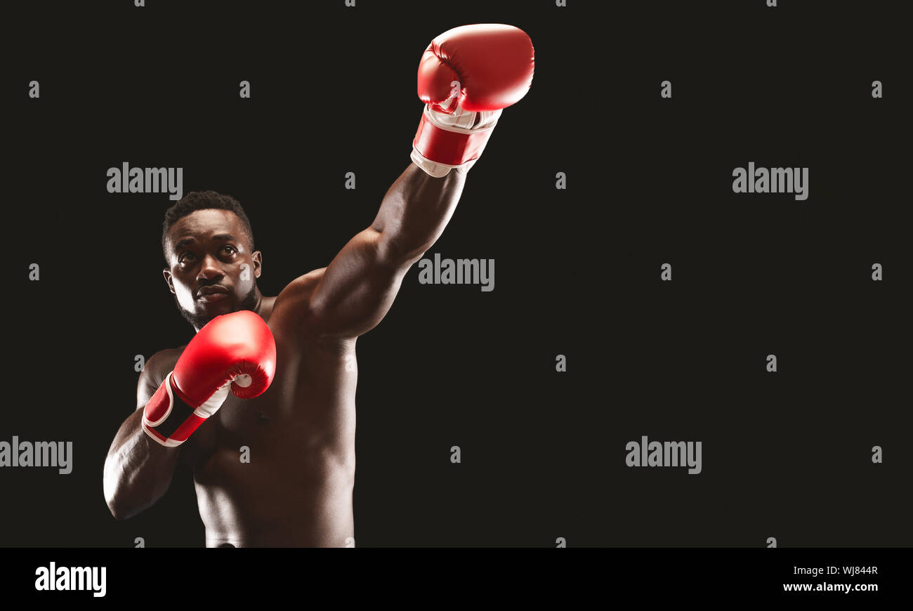 MMA afrikanischen Boxer zeigt Big punch über schwarzen Studio Hintergrund Stockfoto