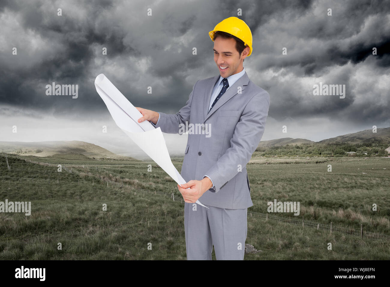 Zusammengesetztes Bild des lächelnden Architekten mit Schutzhelm, die Pläne zu betrachten Stockfoto