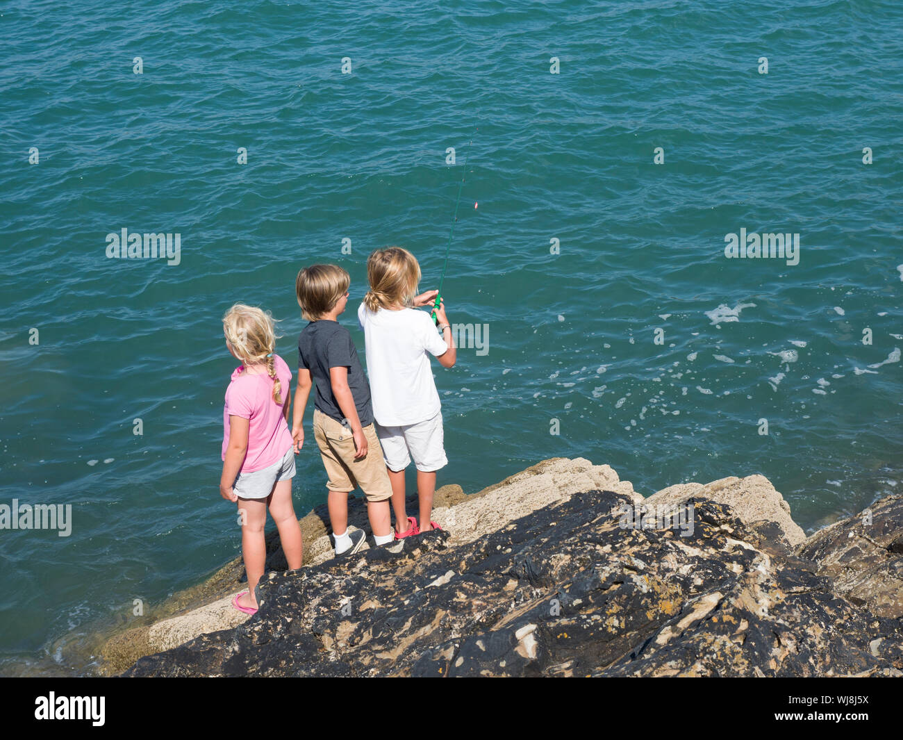 Kinder Angeln von Felsen, Bude, Cornwall, Großbritannien Stockfoto