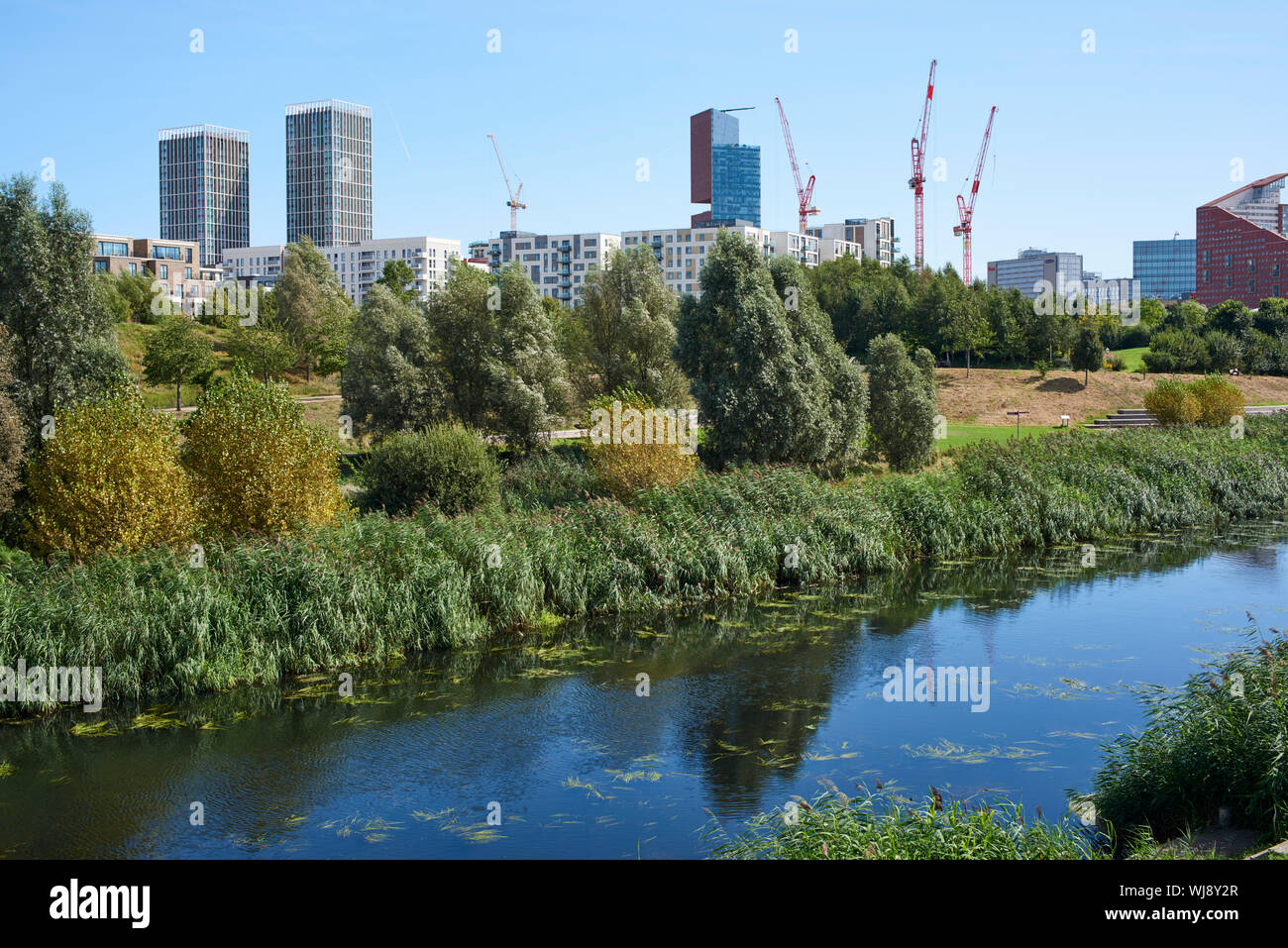 Central Stratford und East Village, East London UK, gesehen von der Queen Elizabeth Olympic Park, mit den Fluss Lea im Vordergrund Stockfoto