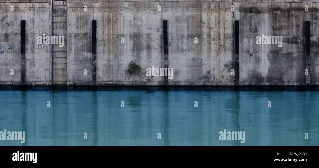 Grunge konkrete Verankerung an der Wand mit Stoßfängern und Metallleiter, Hintergrund Foto Textur Stockfoto