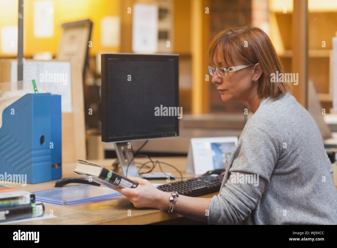 Weibliche Bibliothekar, die ein Buch lesen Sie die Abdeckung vor dem Scannen Stockfoto