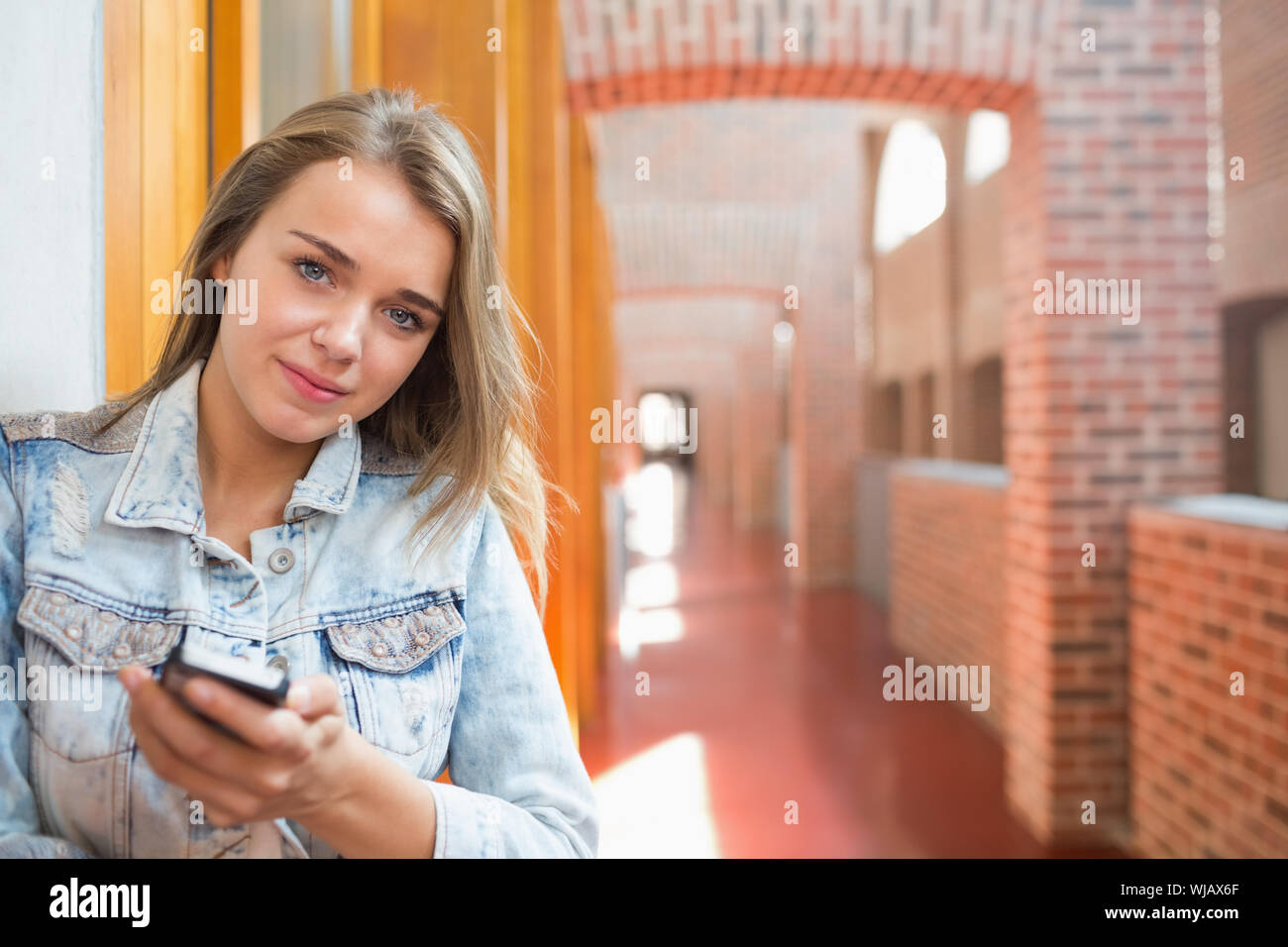 Glückliche Schüler stehen in der Halle eine SMS Stockfoto