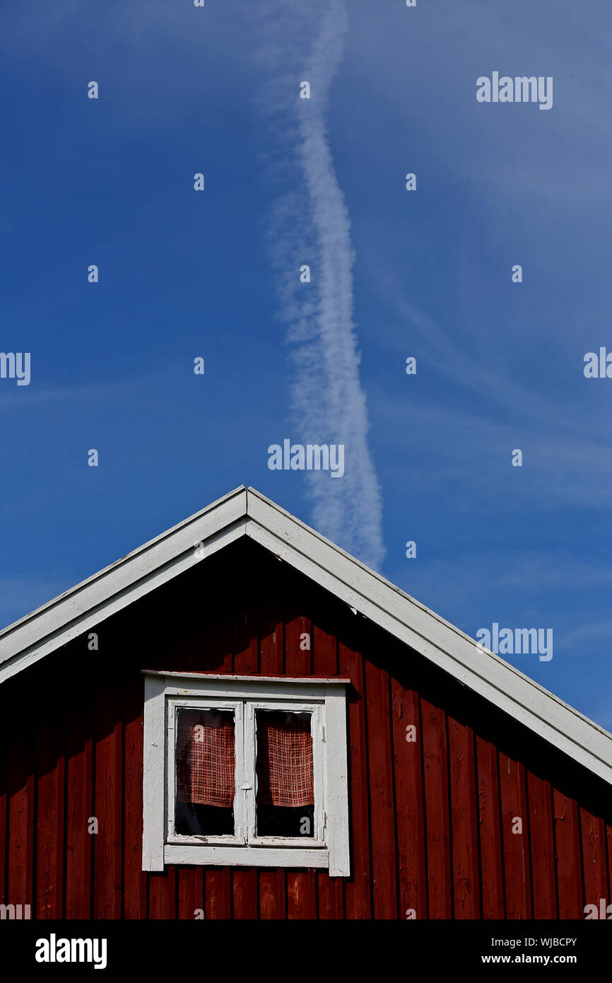 Ein Giebel eines alten Hauses. Flugzeuge Kondensstreifen mit Wolken sind in den klaren blauen Himmel gesehen Stockfoto