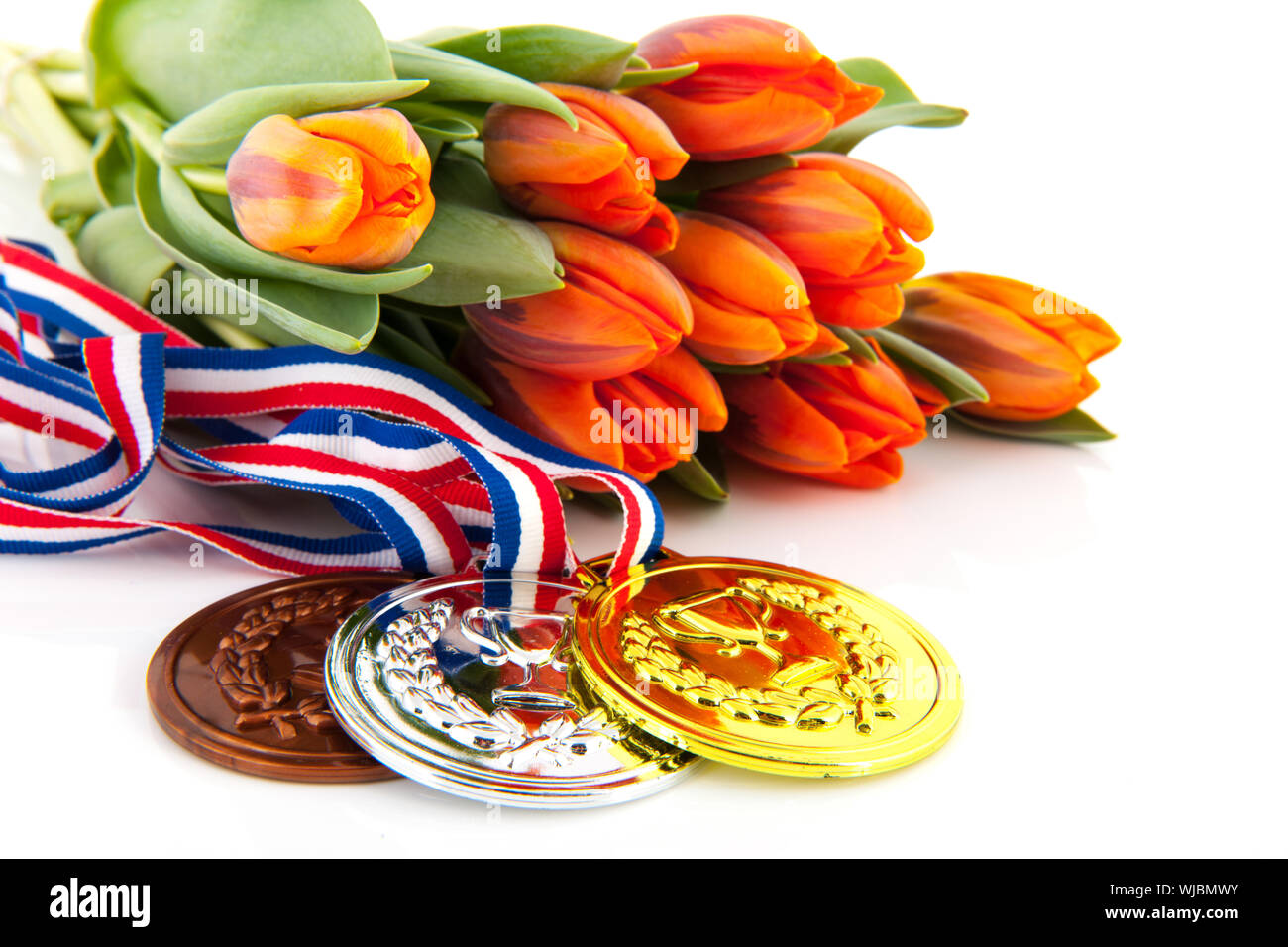 Niederländischen Medaillen in Gold, Silber und Bronze vor orange Tulpen isoliert auf weißem Hintergrund Stockfoto