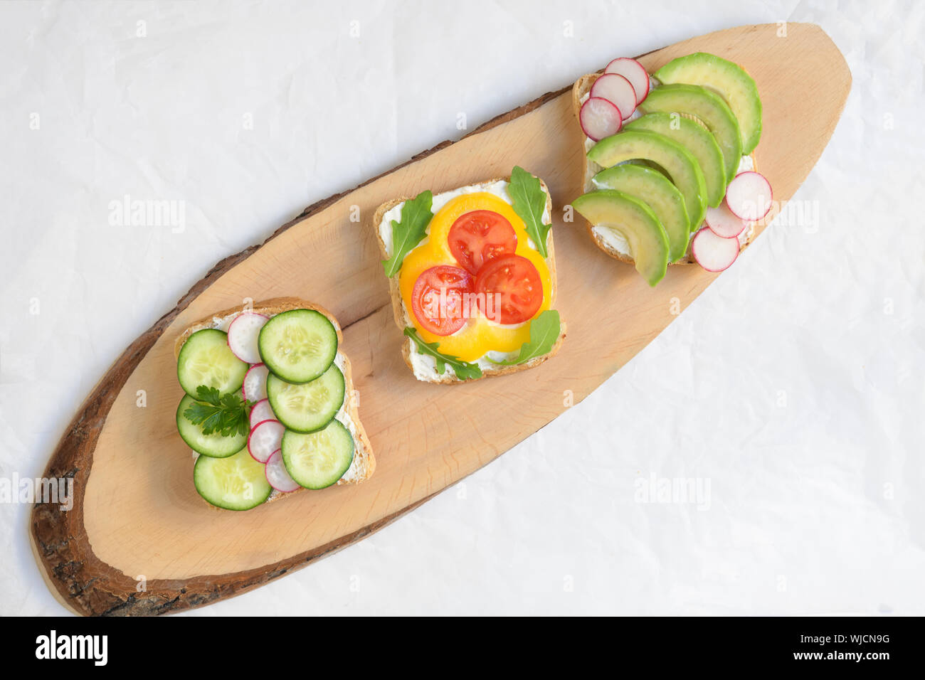 Drei vegetarische o vegan Sandwich mit Avocado, Rettich, Gurke und frischer Käse, gesunden Snack für Kinder und Erwachsene, einfach zuzubereiten, Ansicht von oben, h Stockfoto