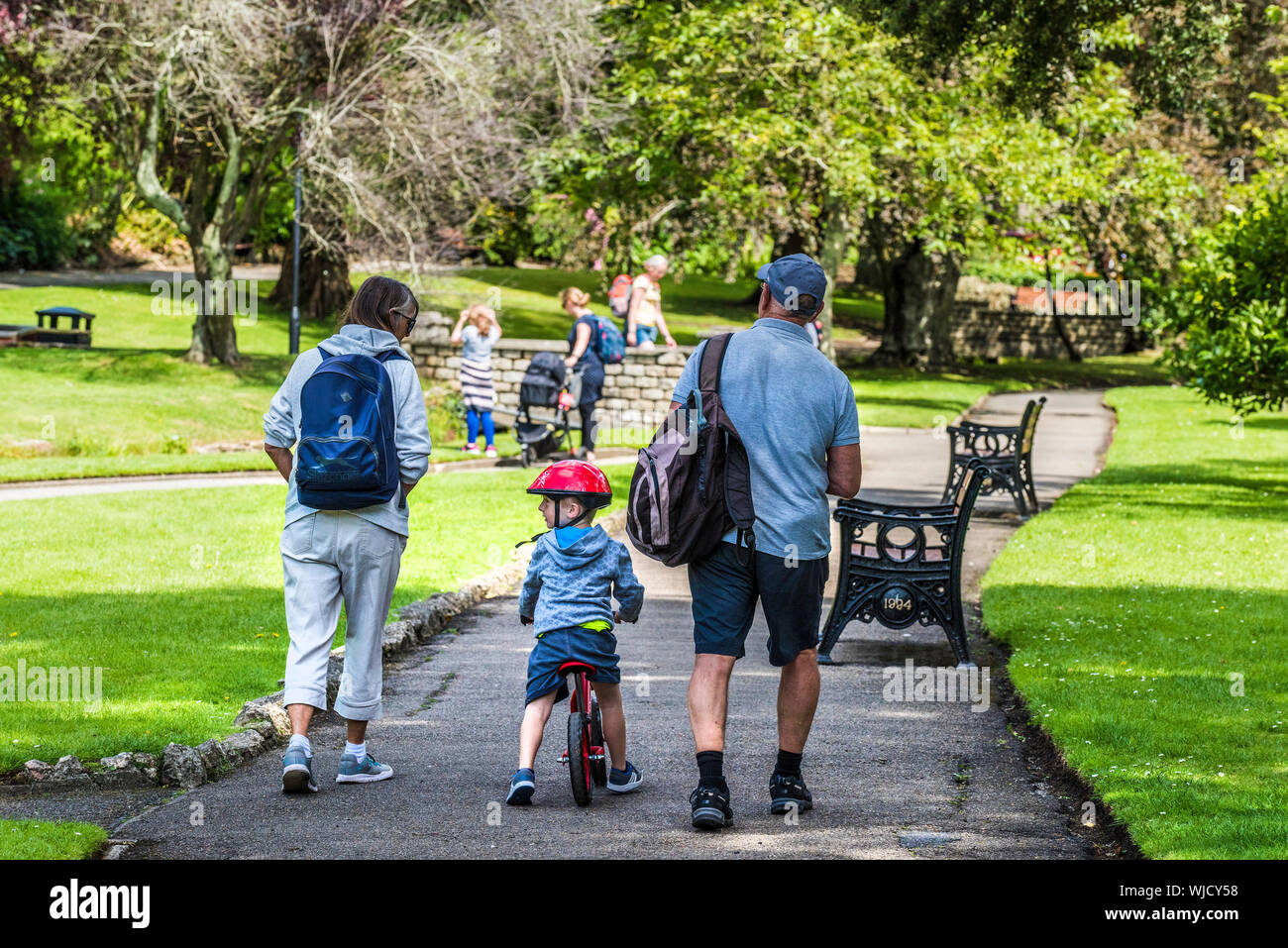 Großeltern gehen durch einen Trenance Park mit ihren kleinen Enkel. Stockfoto