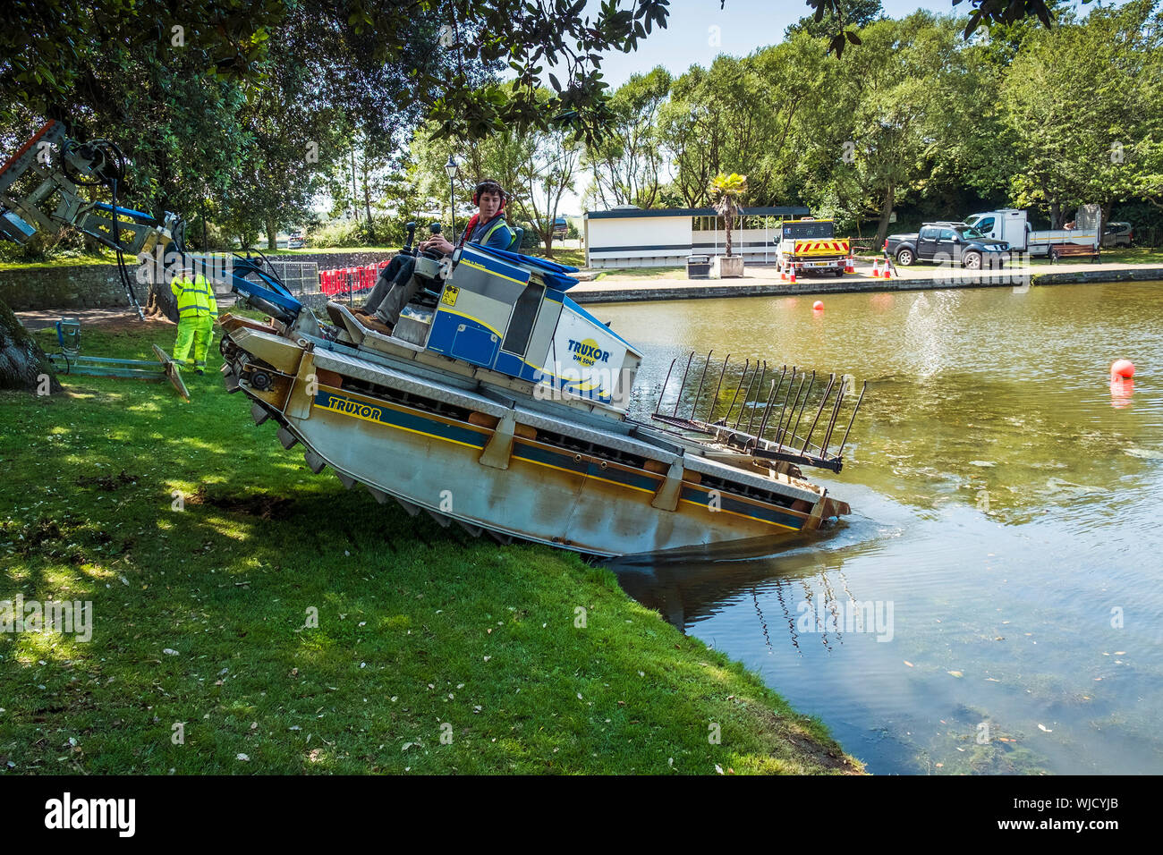 Eine Truxor DM 5045 Selbstfahrende amphibian Toolcarrier vorsichtig rückwärts auf die Kontrolle invasiver Unkräuter in Trenance See zum Bootfahren in Newquay zu arbeiten Stockfoto