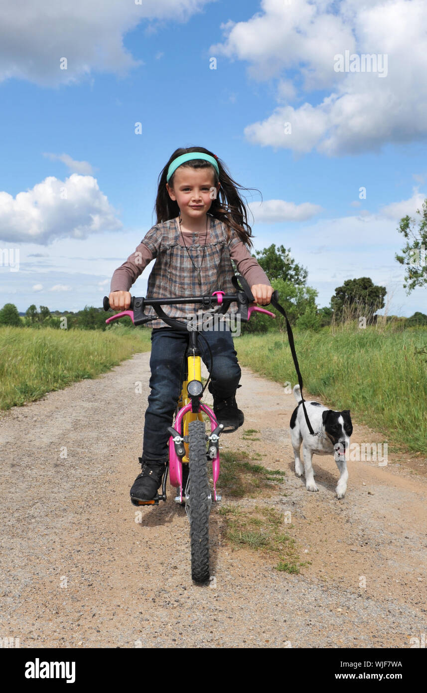 Kleines Mädchen mit ihrem Jack Russel Terrier auf einem Fahrrad Stockfoto