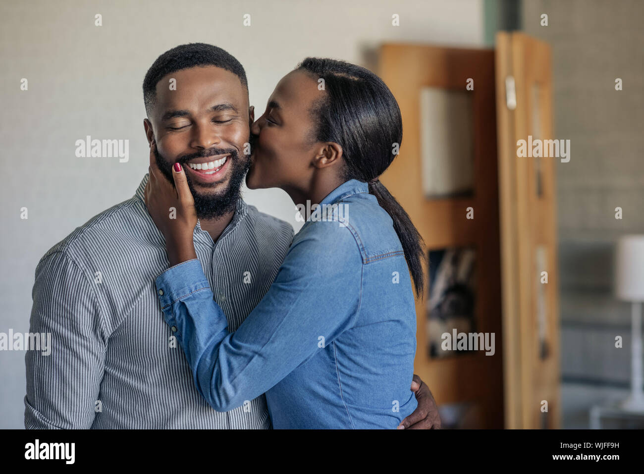 Liebevolle afrikanische amerikanische Frau ihrem Mann Küssen auf die Wange Stockfoto