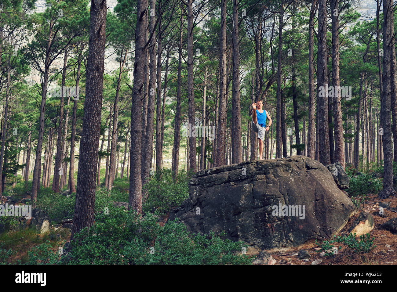 Mann, die verlängerte Hand bis zu den Zehenspitzen in einen Wald darstellen Stockfoto