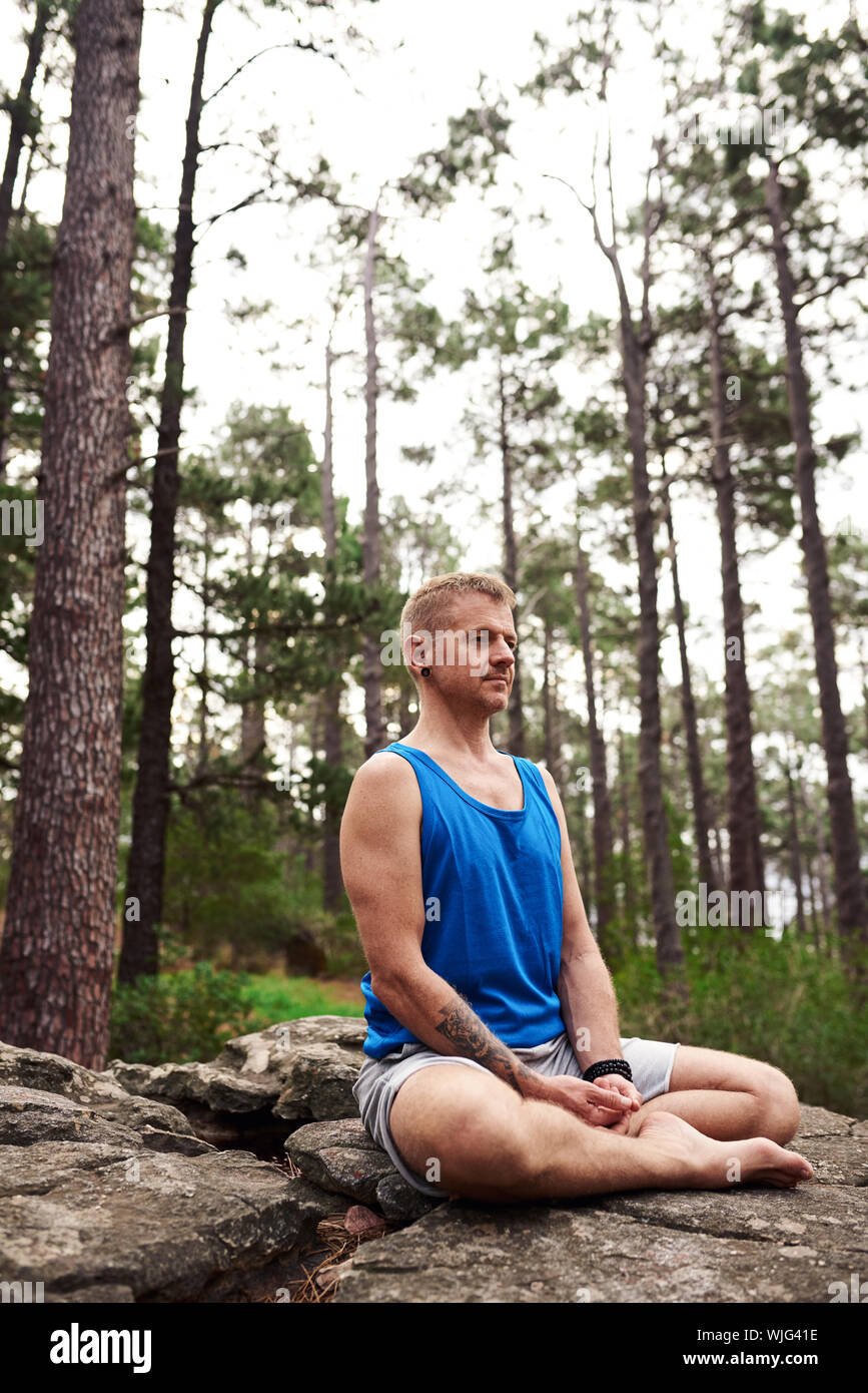 Mann sitzt auf einem Felsen und Meditieren in den Wald Stockfoto