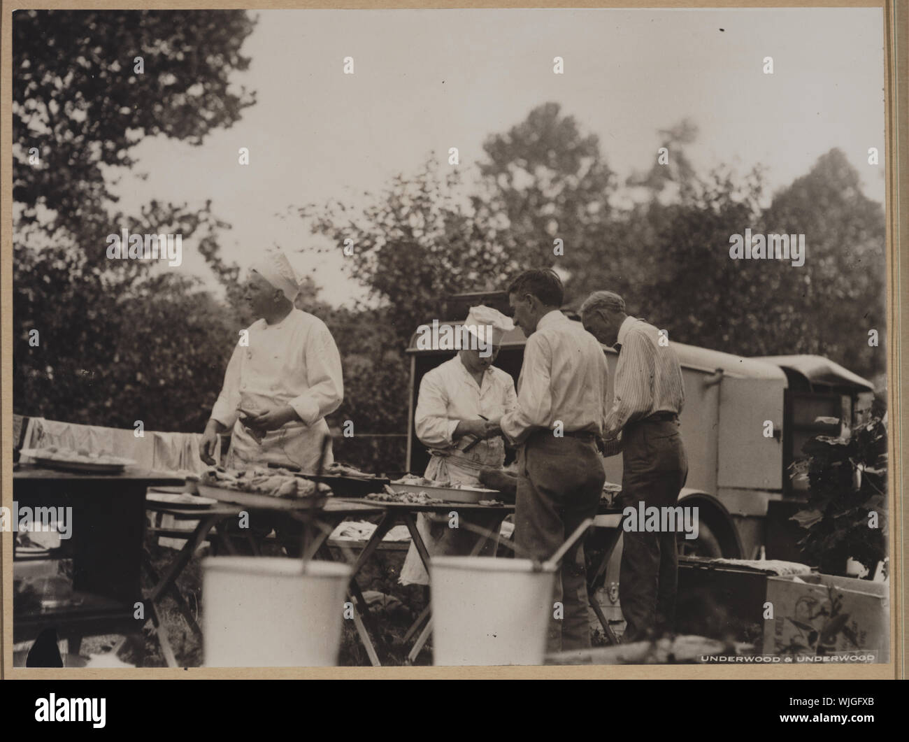 Henry Ford und Harvey Firestone Unterstützung zwei Köche durch Schälen Kartoffeln zu einem Ford-Edison camping Reise Stockfoto