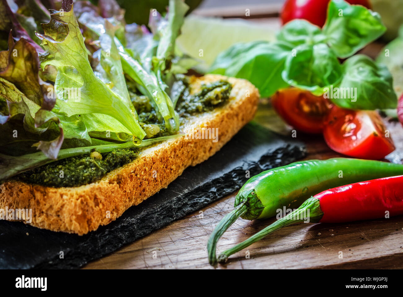 In der Nähe von Brot mit Salat serviert am Tisch von Chilly Peppers und Basilikum Stockfoto