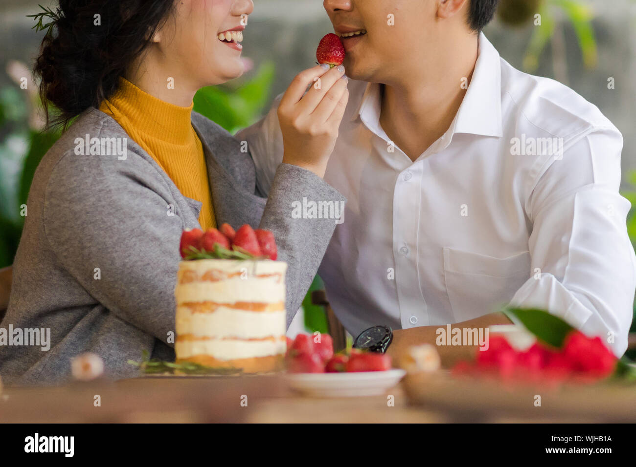 Mittelteil der Frau Fütterung Erdbeere Mann im Restaurant Stockfoto