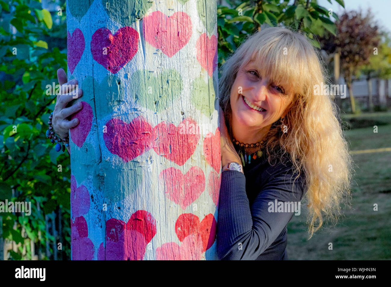 Gerne Frau mittleren Alters, von Herzen posing abgedeckt BC Hydro Pol, Stockfoto