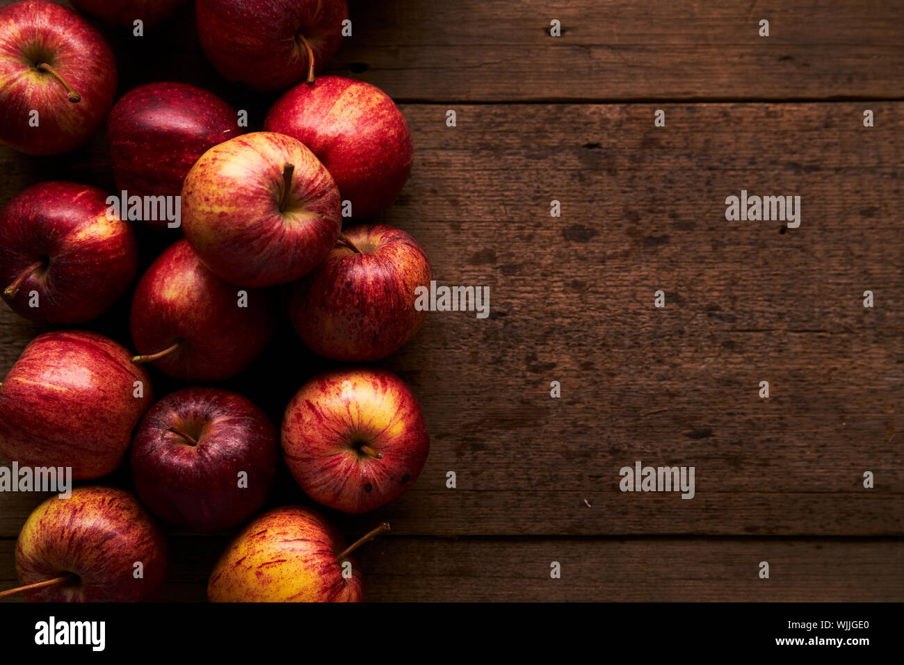 Deep Red Royal Gala Äpfel auf einem rustikalen Holztisch mit sanfter Beleuchtung Stockfoto