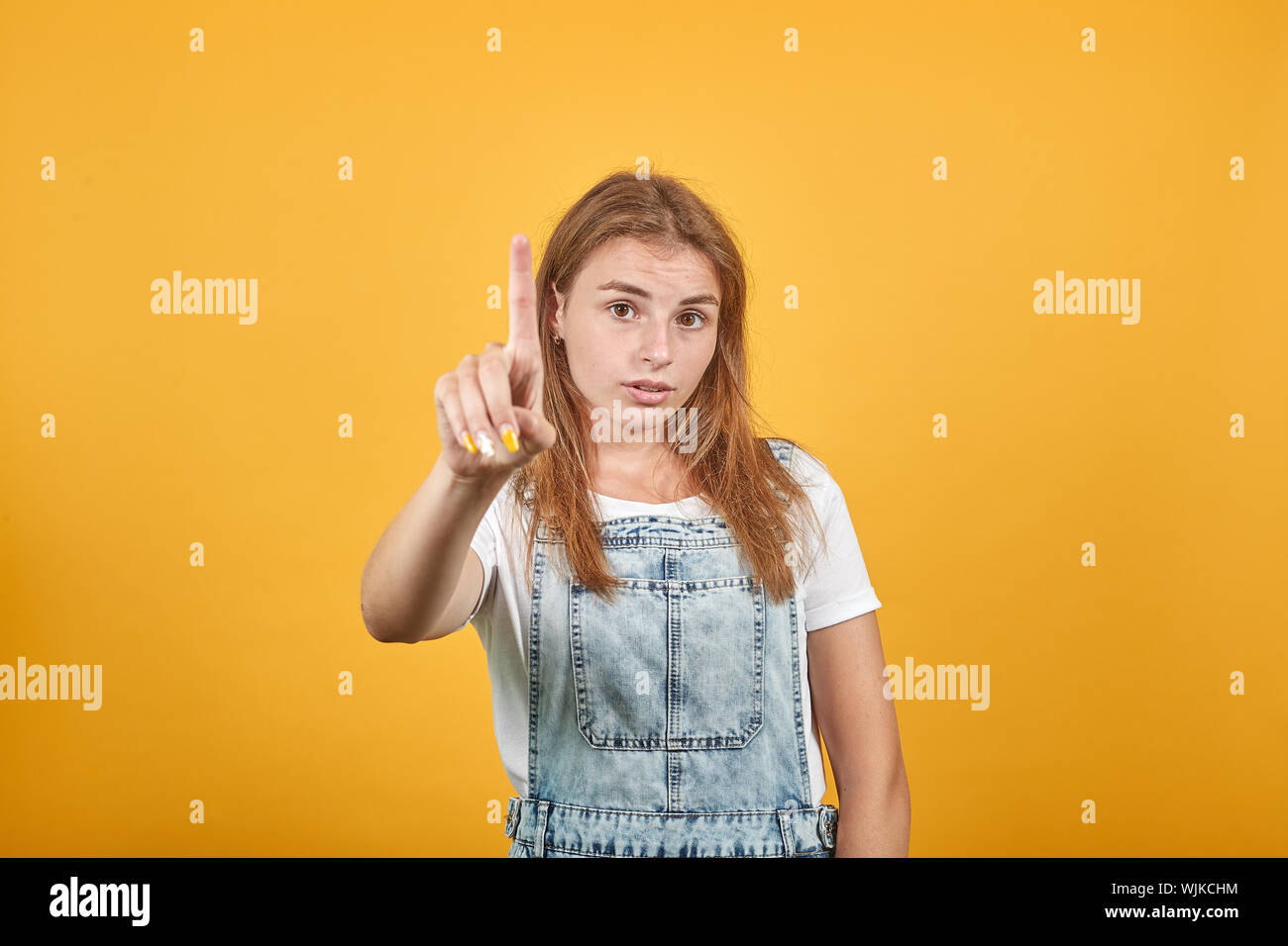 Junge Frau tragen weiße t-shirt, über orange Hintergrund zeigt Emotionen Stockfoto